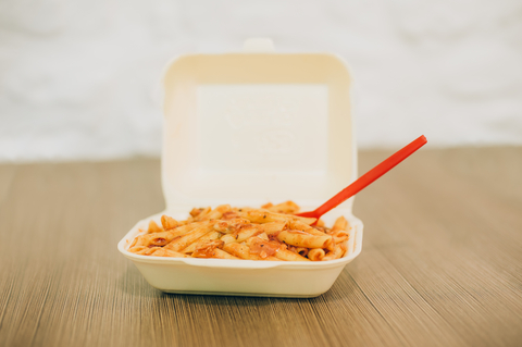 Pasta with red sauce in a white takeout container