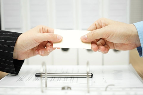 Image of Two Hands Exchanging a Business Card